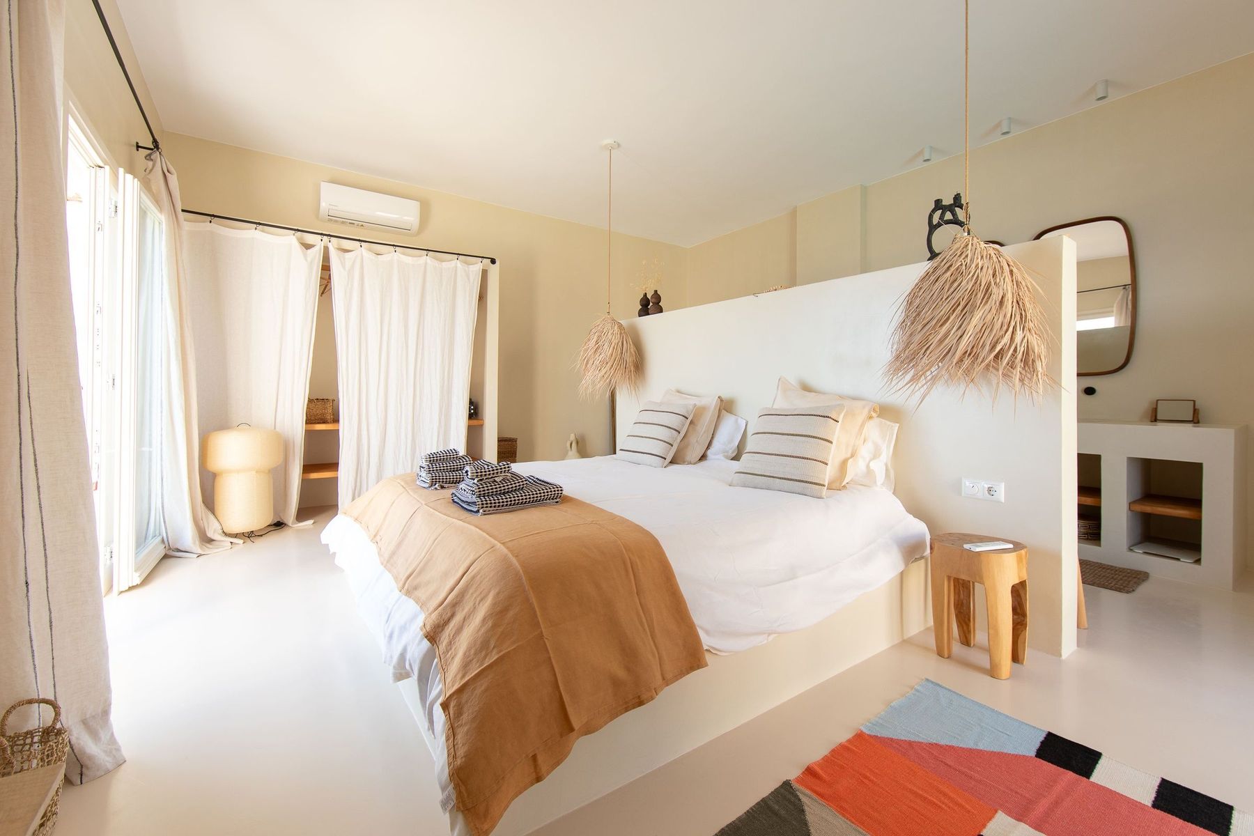 Bedroom with a standing mirror and a woven rug