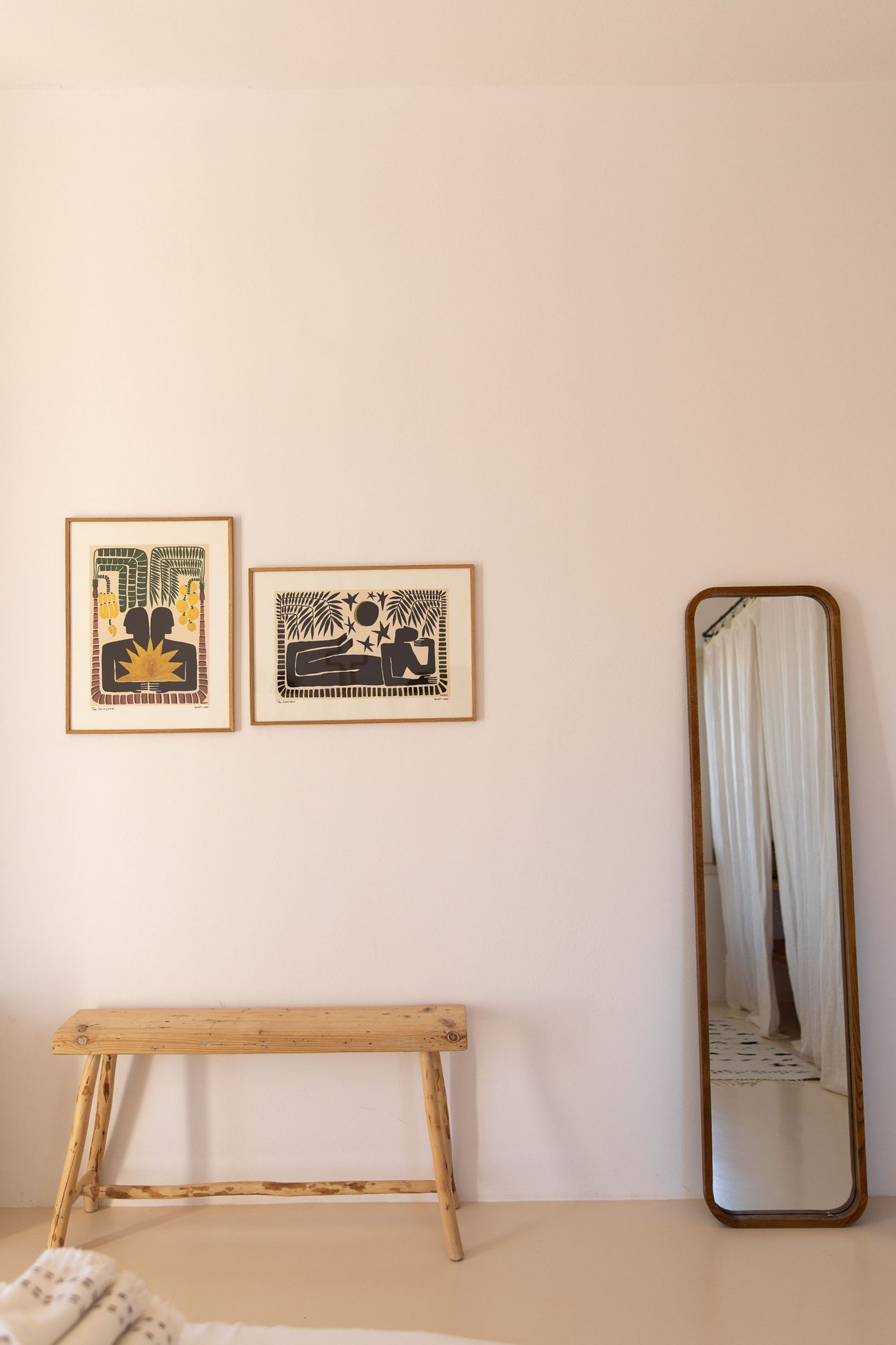 A bench and a leaning mirror against a white wall