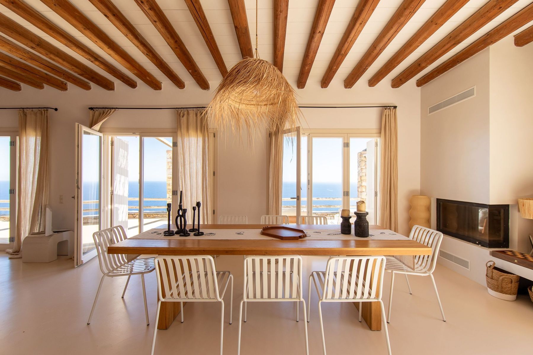 The indoor dining table beneath a woven pendant